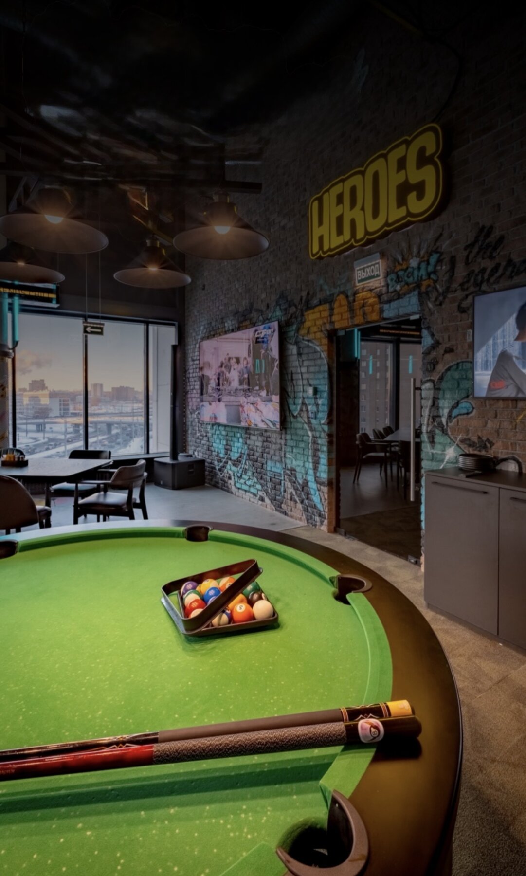 HEROES neon over the pool table with city view.
