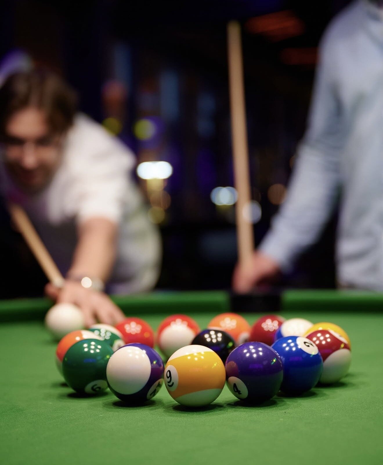 Pool game close-up with two players cuing up.