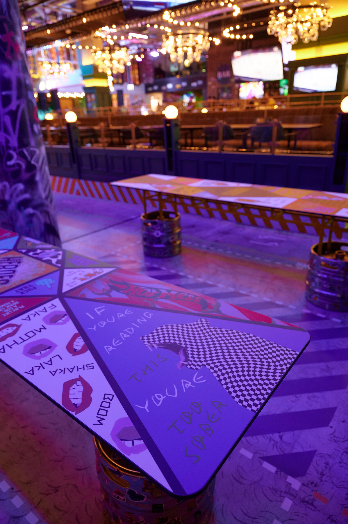 Beer pong tables under purple lights with neon backdrop.