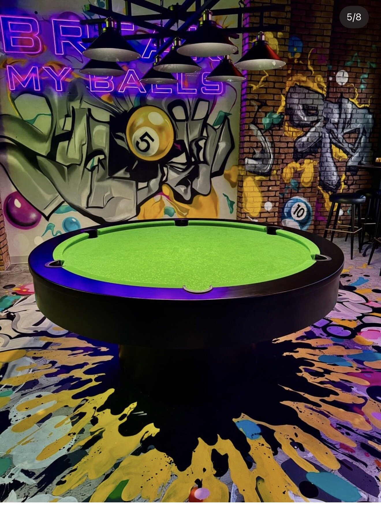 Round pool table under the BREAK MY BALLS neon.